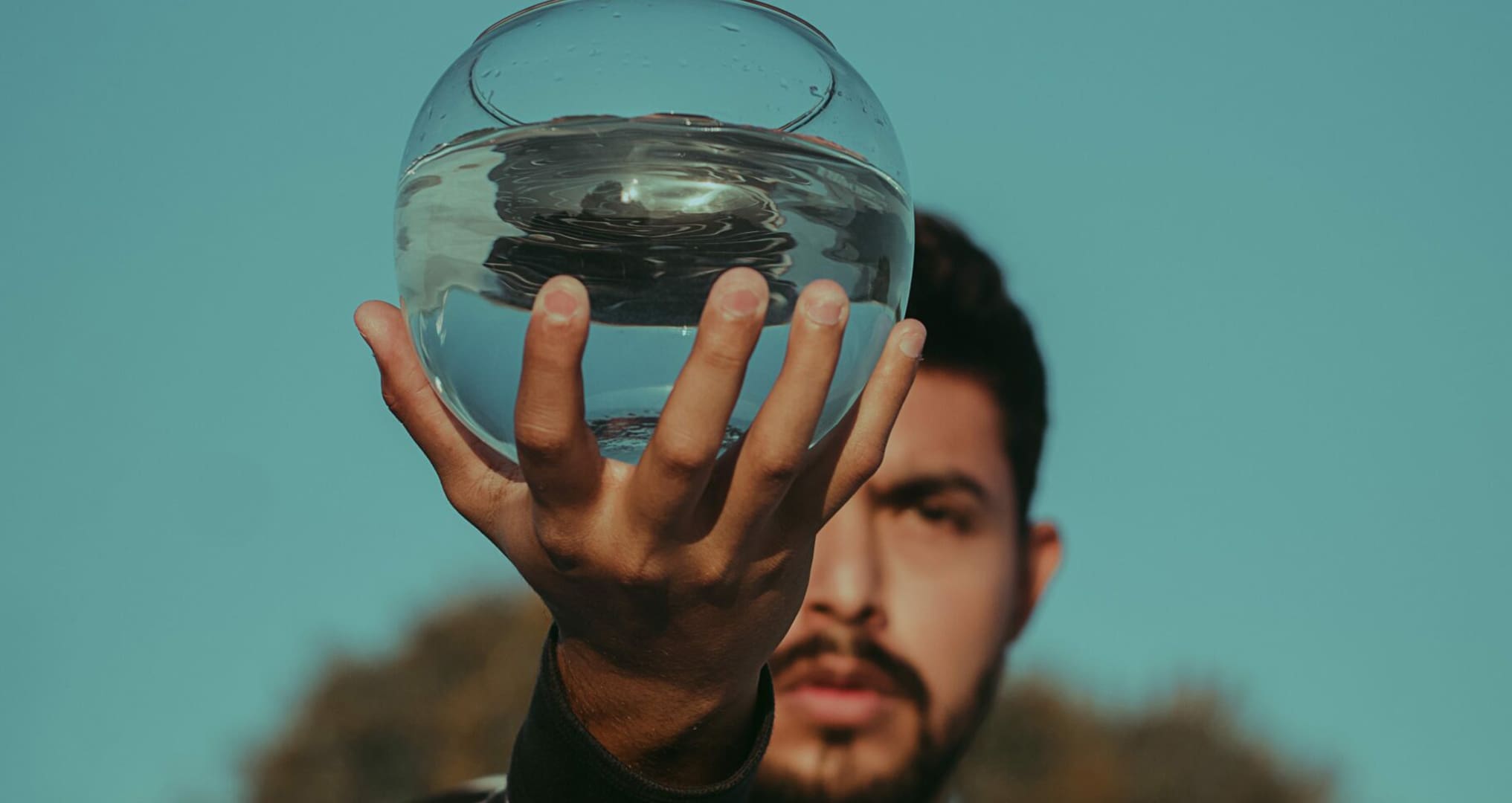 man holding fishbowl of water