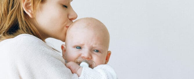 woman kissing child on forehead