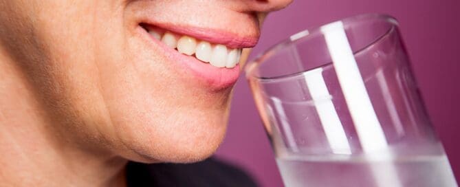 woman smiling and drinking a glass of water