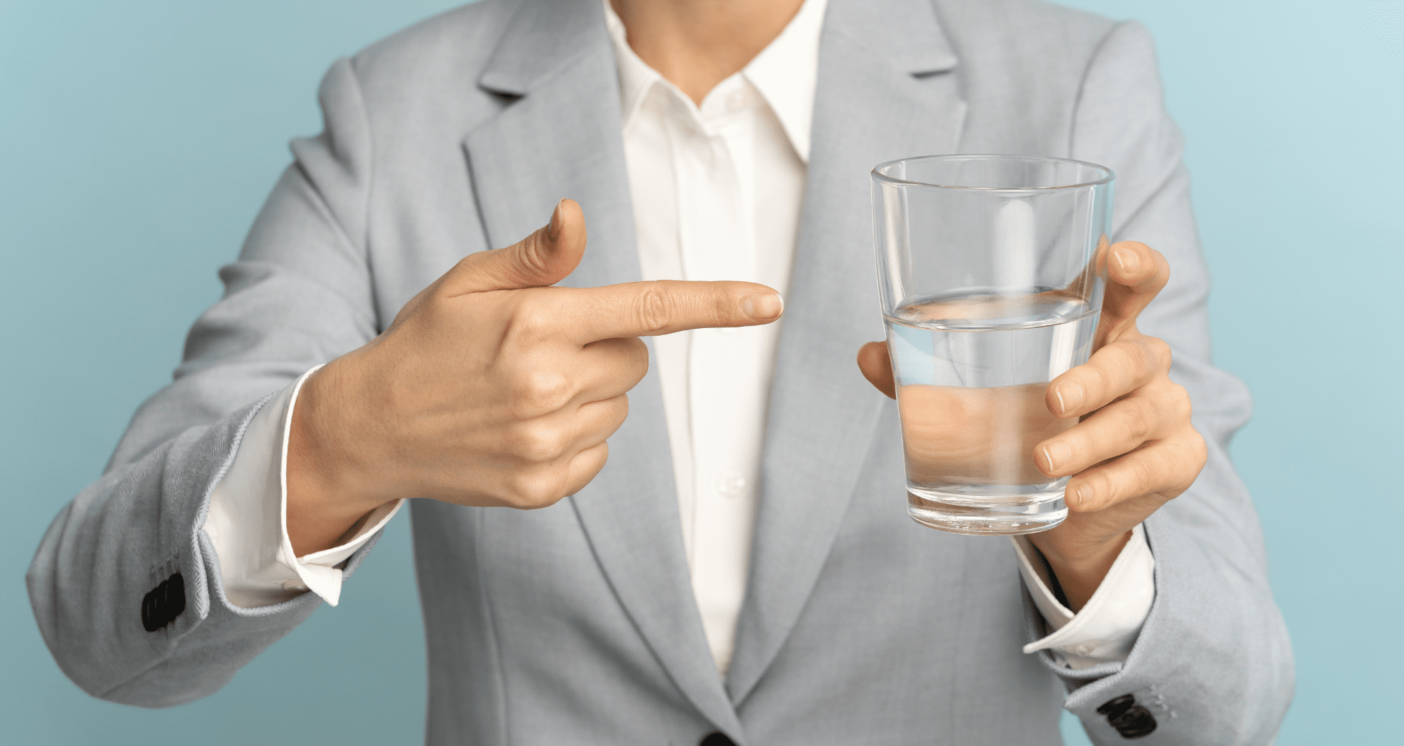 woman holding and pointing to a glass of water