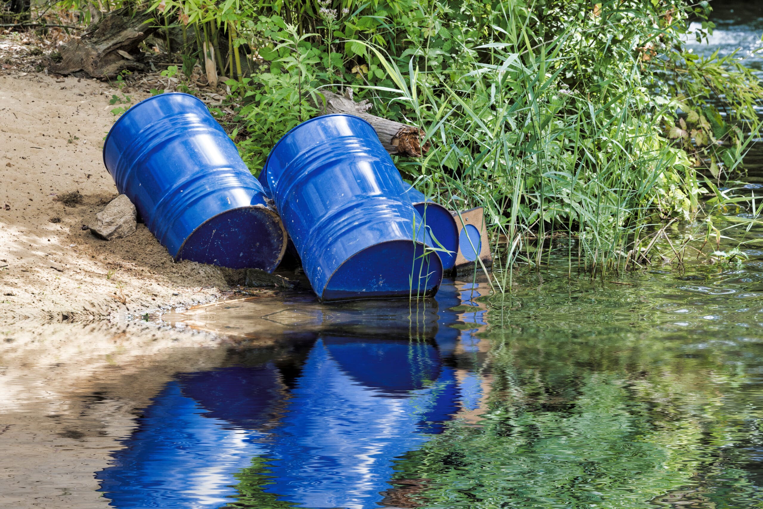 blue toxic chemical barrels sitting along the river’s edge.