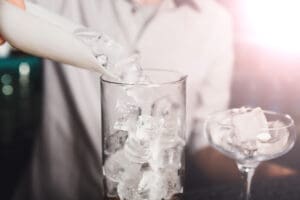 Barman's hands in bar interior making alcohol cocktail.